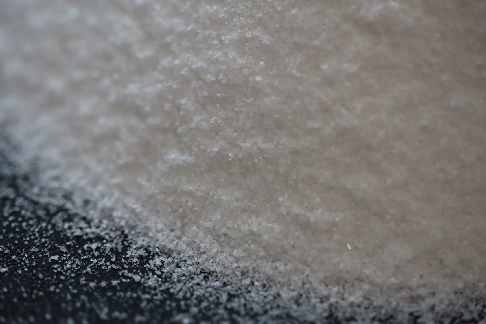 A close-up photograph of light-coloured grains on a dark surface